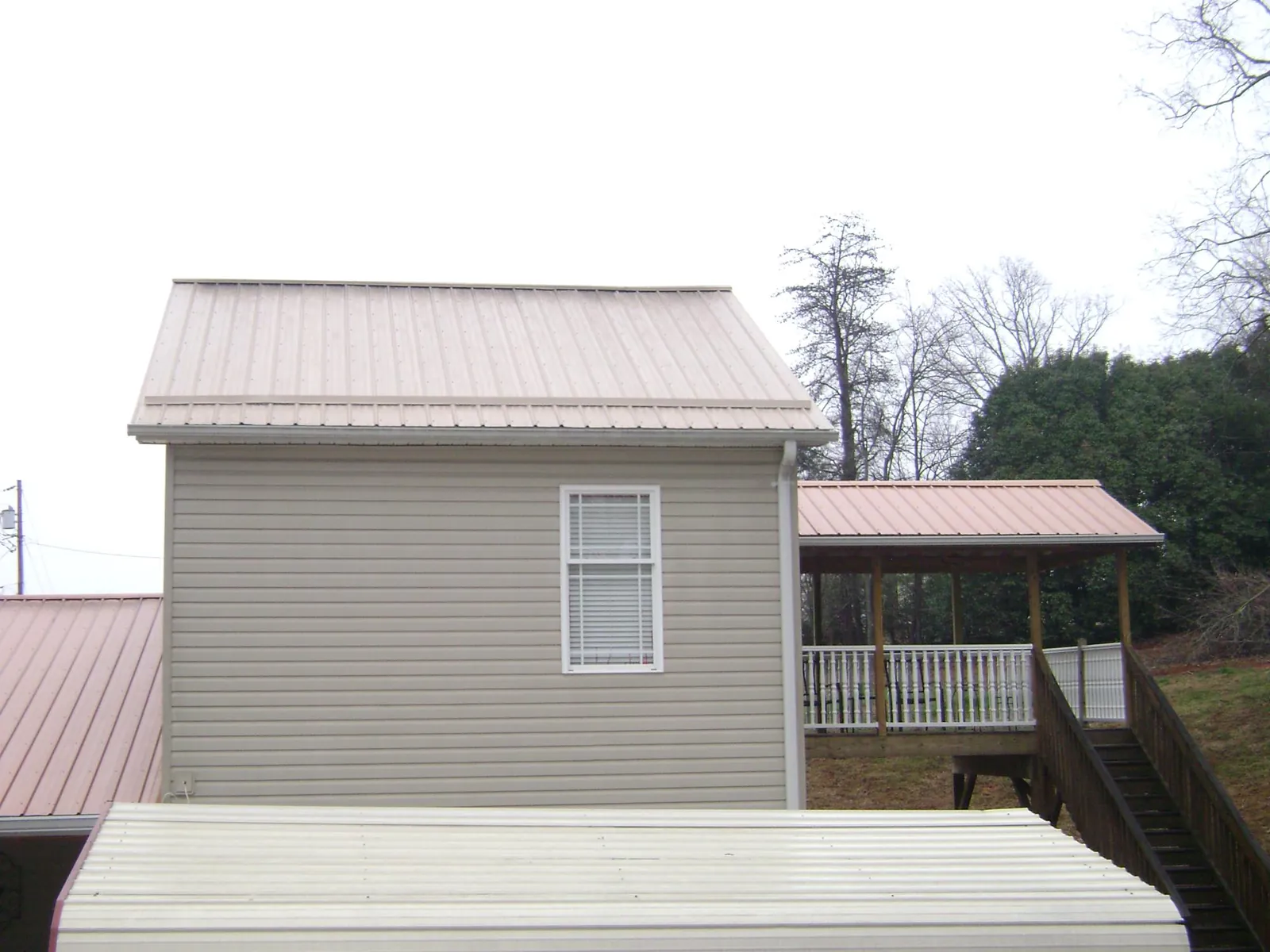 Tan metal roofs on a two story addition and attached porch, from a Roof Replacement job in Industry